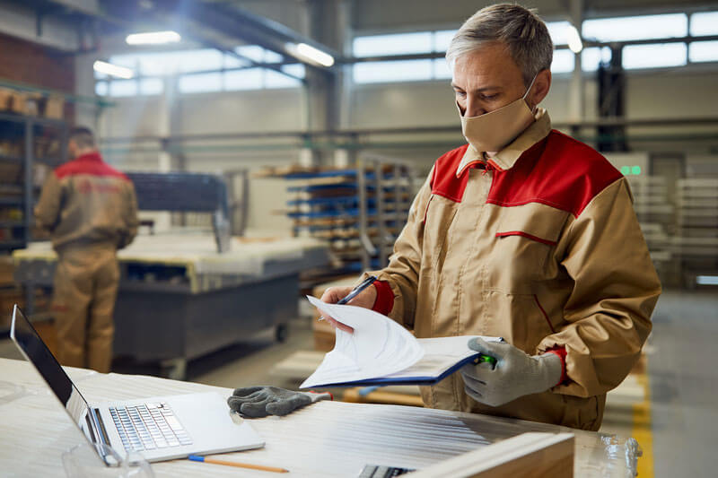 Manufacturing specialist reviewing production records on the factory floor